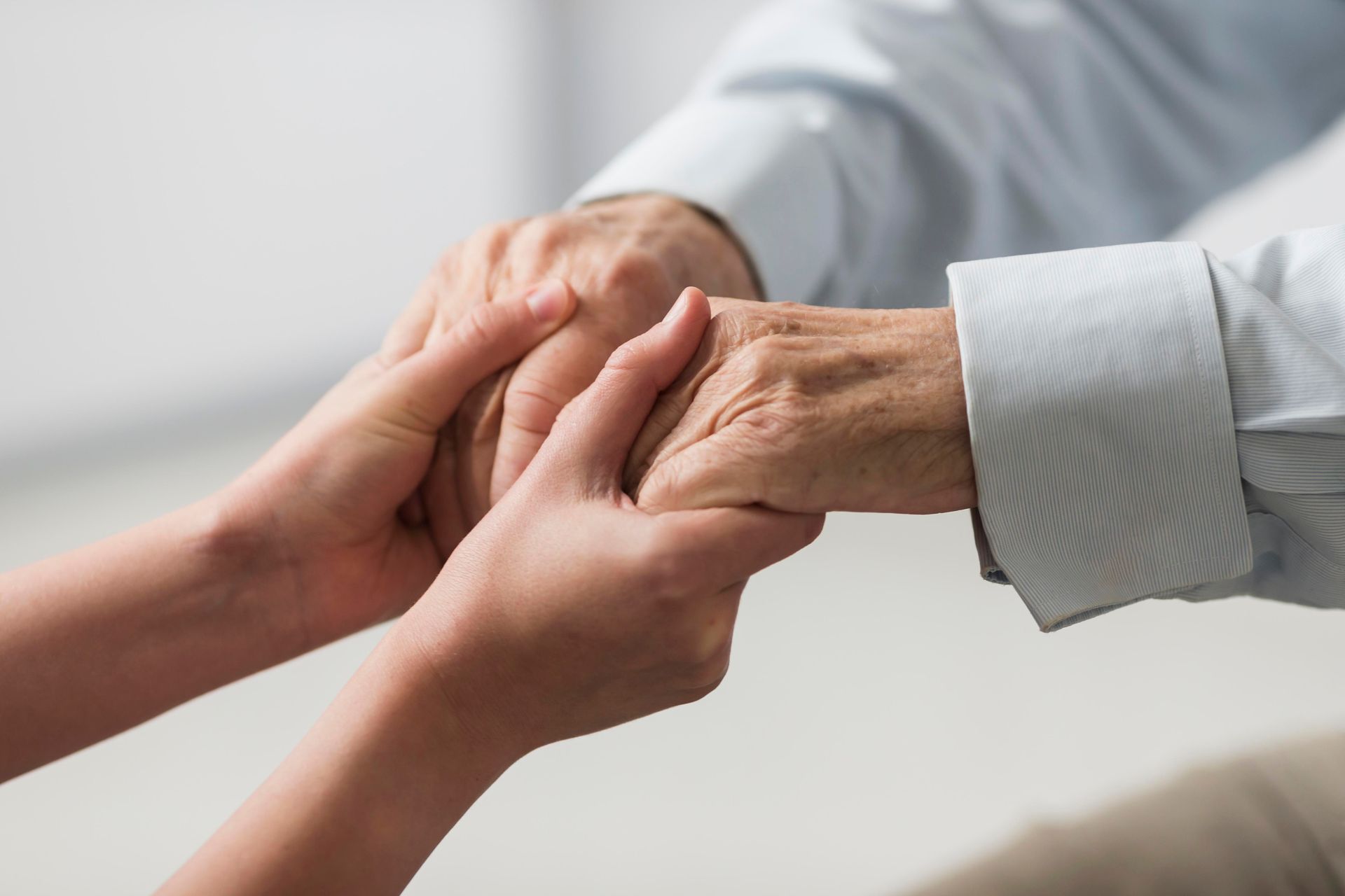 Nurse holding a senior man's hands with sympathy