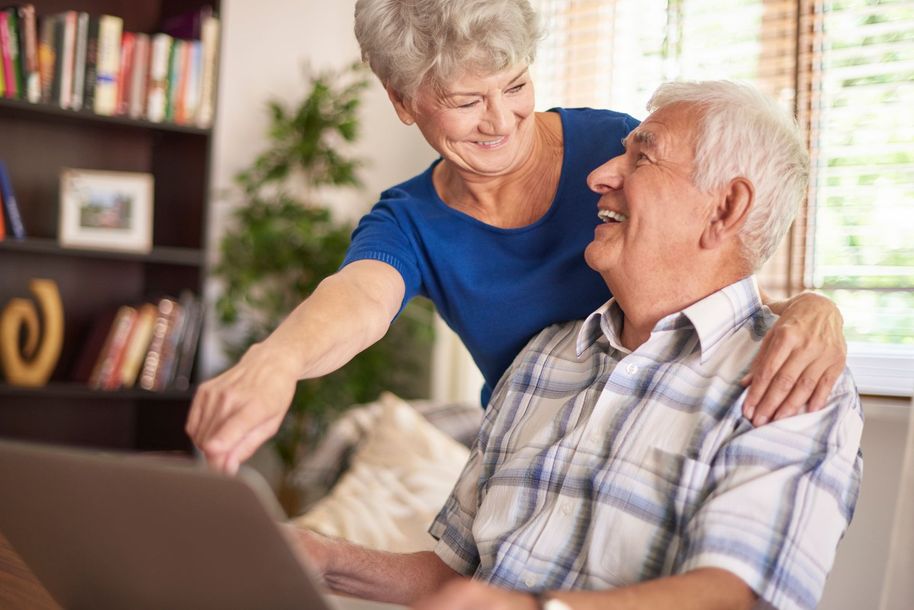 An elderly couple using their laptop together
